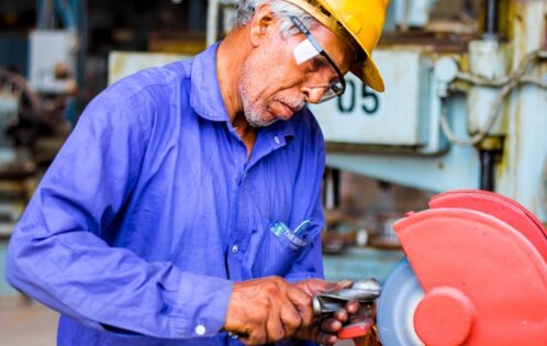man grinding metal tool in industrial machinery