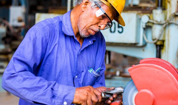 man grinding metal tool in industrial machinery